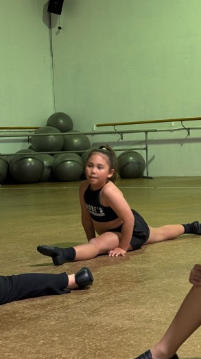 Student practicing splits in a class at Simone's School of Performing Arts, demonstrating flexibility and confidence in kids dance classes near me, children's dance classes near me, dance studios for kids near me, and ballet classes for kids near me.